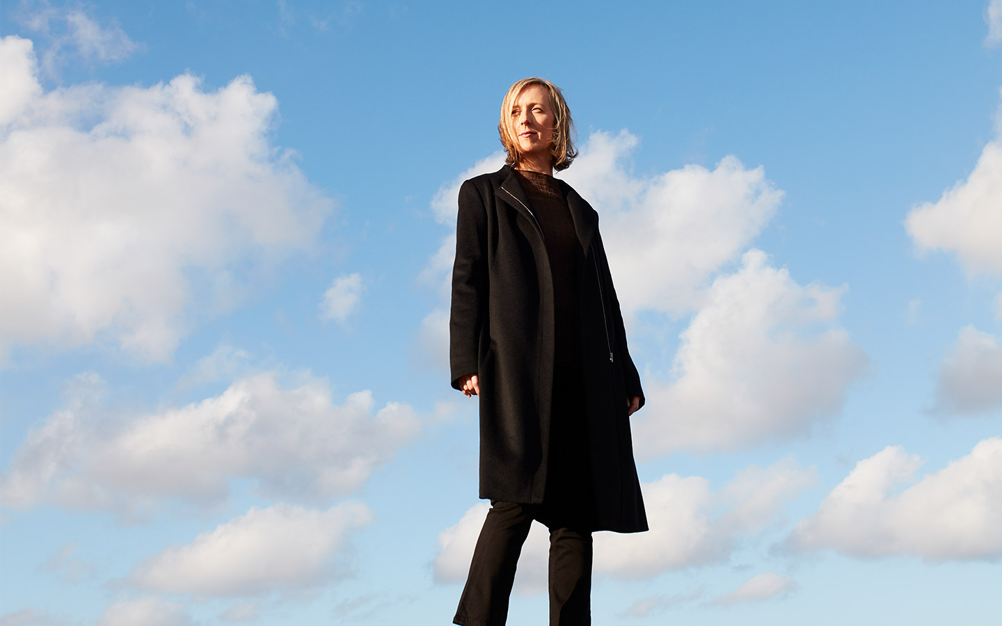 A photo Cellist Melissa Barnard against a vibrant blue sky