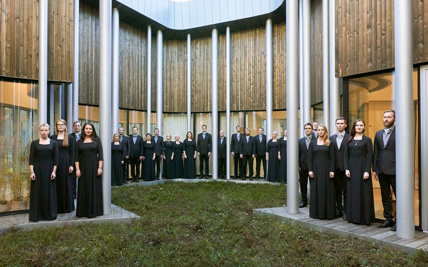 The Estonian Philharmonic Chamber Choir standing between the pillars of a building