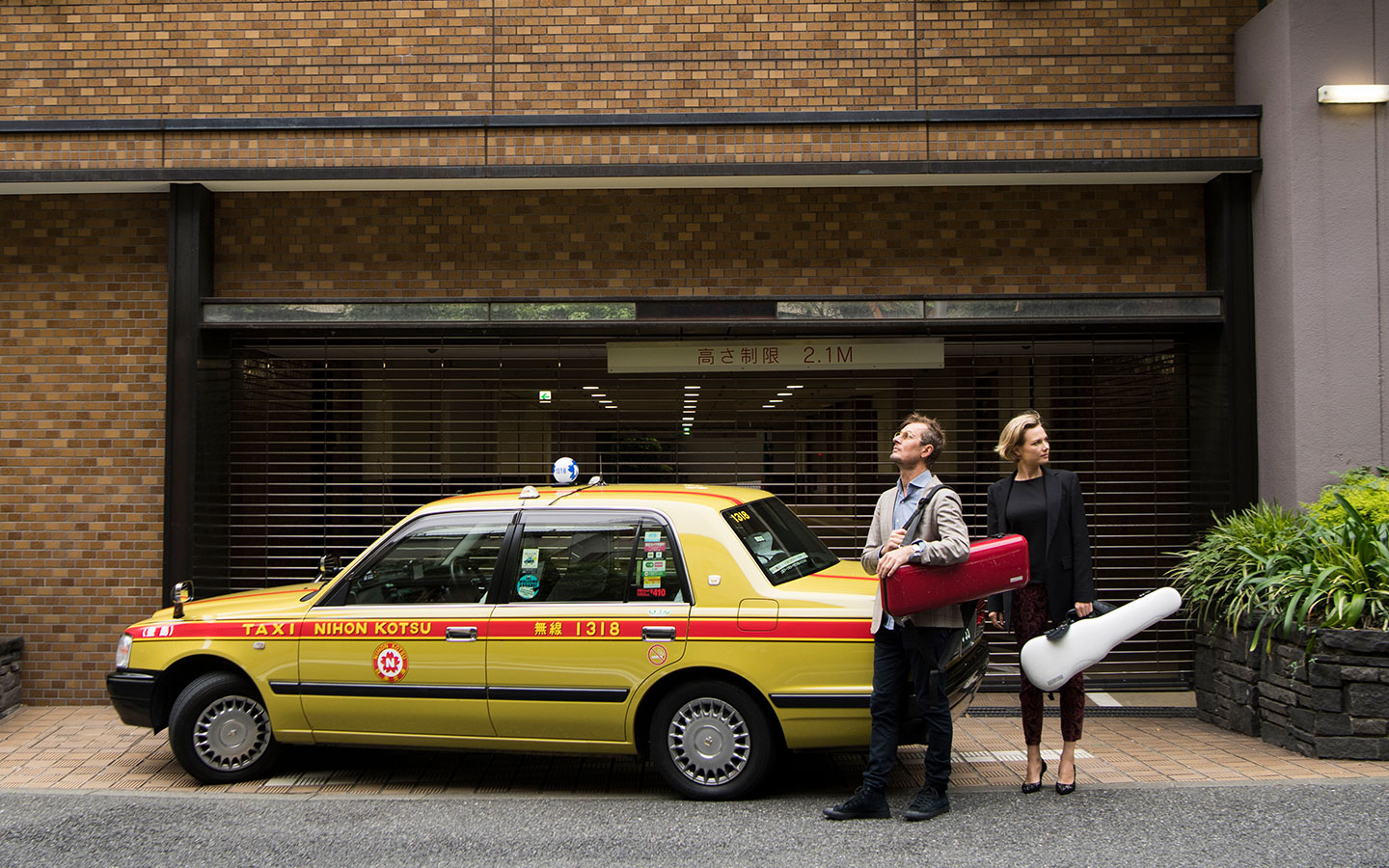 ACO Artistic Director Richard Tognetti and Principal Violin Satu Vänskä standing in front of a taxi in Japan