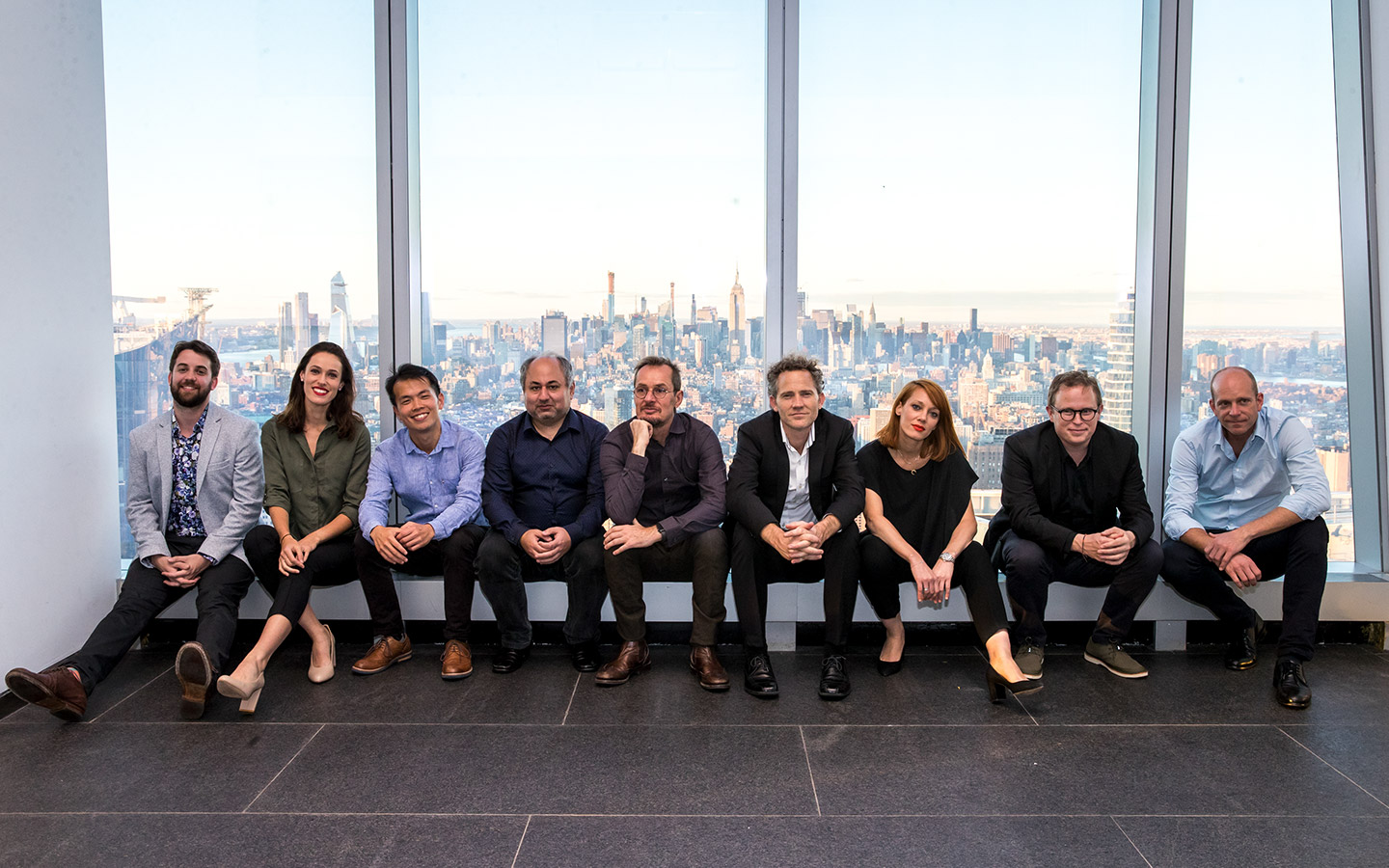 Members of the ACO sitting on a ledge with the New York skyline behind them